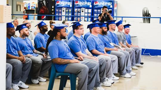 Two rows of incarcerated people at their graduation ceremony.